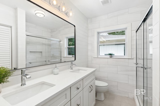 bathroom with tile walls, visible vents, toilet, and a sink