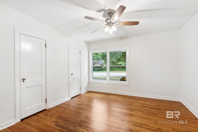 empty room with baseboards, wood finished floors, and a ceiling fan
