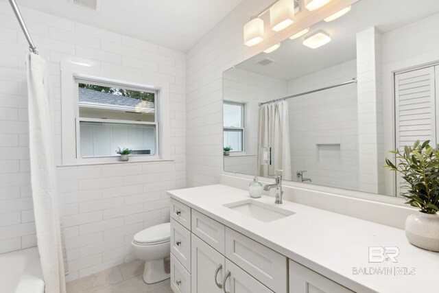 full bathroom featuring tile walls, shower / tub combo, vanity, toilet, and tile patterned floors