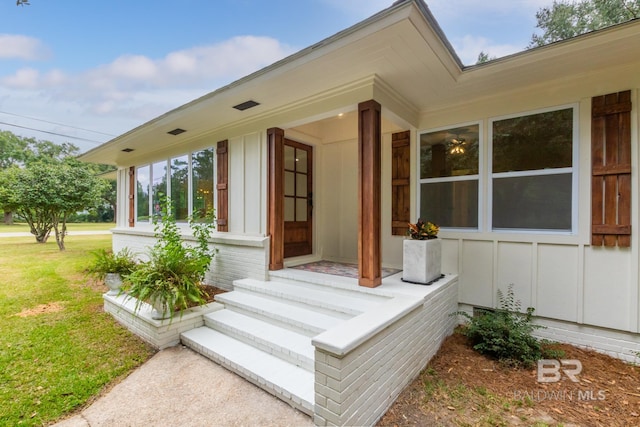 doorway to property featuring a lawn and covered porch