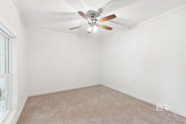 carpeted empty room with baseboards, ornamental molding, and a ceiling fan
