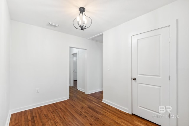 interior space featuring baseboards, visible vents, a notable chandelier, and wood finished floors