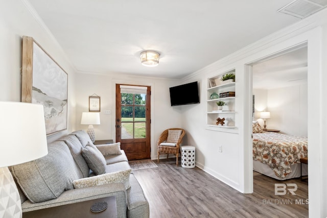 living room with baseboards, visible vents, ornamental molding, and wood finished floors