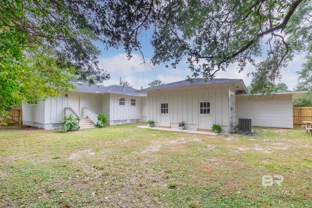 back of property featuring central AC unit and a lawn