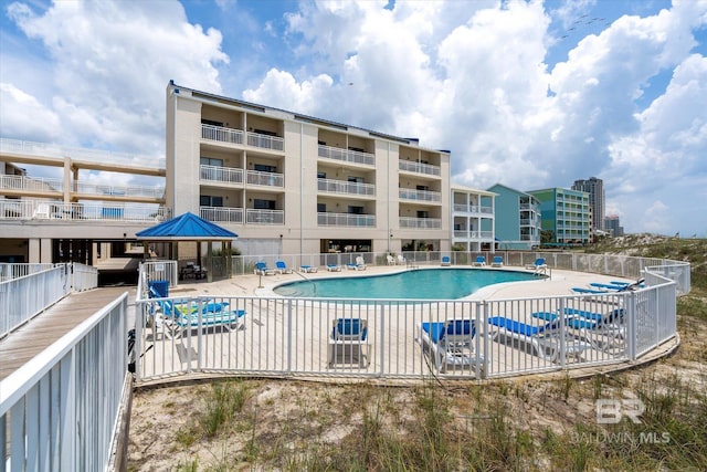 community pool with a patio area and fence