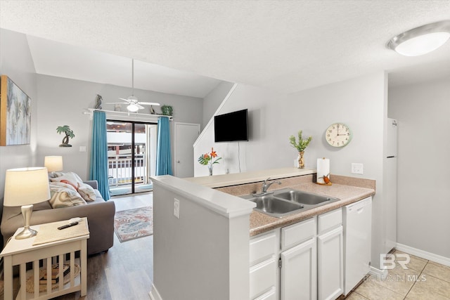 kitchen featuring white cabinetry, a peninsula, a sink, dishwasher, and open floor plan