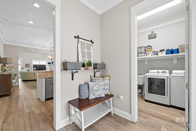 clothes washing area featuring washer and dryer, light wood-type flooring, and crown molding