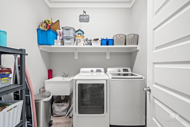 laundry area featuring wood-type flooring, sink, and washing machine and clothes dryer