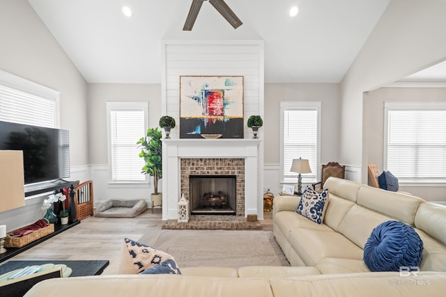 living room featuring a brick fireplace, light hardwood / wood-style floors, and vaulted ceiling