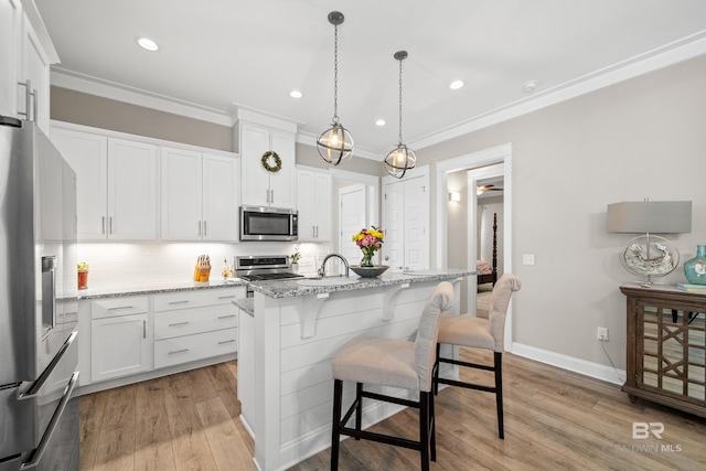 kitchen featuring a center island with sink, appliances with stainless steel finishes, light hardwood / wood-style floors, light stone counters, and white cabinetry