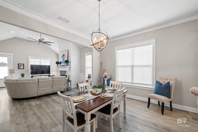 dining room with ceiling fan with notable chandelier, ornamental molding, lofted ceiling, and light wood-type flooring