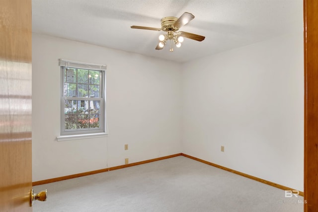 unfurnished room with carpet floors, a textured ceiling, baseboards, and a ceiling fan