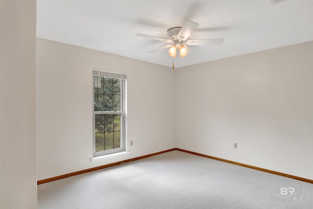 carpeted spare room with ceiling fan and baseboards