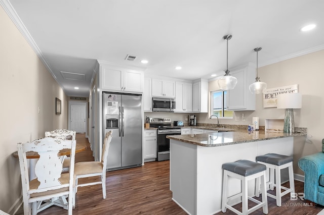 kitchen featuring hanging light fixtures, white cabinets, dark hardwood / wood-style floors, appliances with stainless steel finishes, and kitchen peninsula