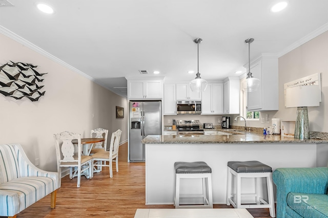 kitchen with pendant lighting, sink, light hardwood / wood-style floors, appliances with stainless steel finishes, and kitchen peninsula