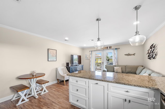 kitchen featuring ornamental molding, pendant lighting, wood-type flooring, and white cabinets