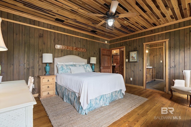bedroom featuring wooden walls, ceiling fan, connected bathroom, and wood-type flooring