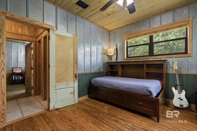 bedroom with wooden ceiling, a wainscoted wall, wood finished floors, and visible vents