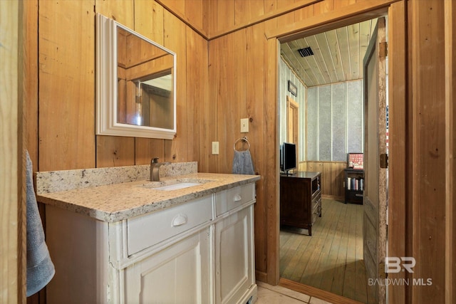 bathroom featuring vanity, wood walls, wood finished floors, and visible vents