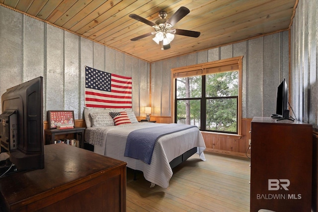 bedroom featuring light wood-style floors, a ceiling fan, wood ceiling, and wooden walls