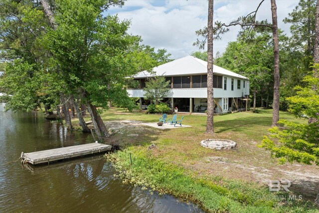 rear view of house featuring an outdoor fire pit, a sunroom, a water view, a patio area, and a yard