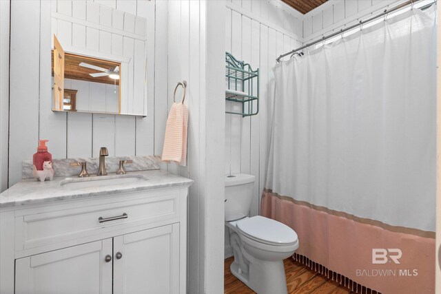 full bath with ceiling fan, wood finished floors, curtained shower, vanity, and toilet