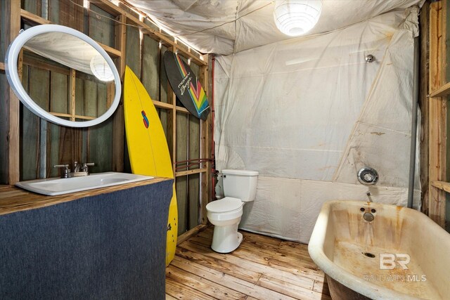 bathroom with a freestanding bath, vanity, toilet, and hardwood / wood-style flooring