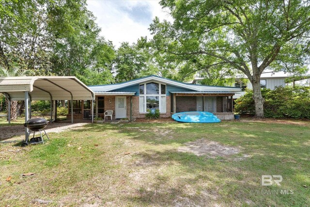 back of house featuring a lawn, a carport, a sunroom, and brick siding