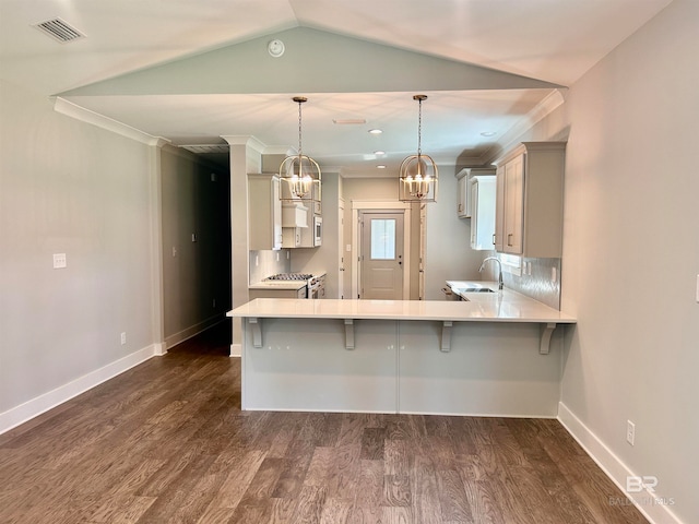 kitchen with dark wood-type flooring, hanging light fixtures, a kitchen bar, and kitchen peninsula