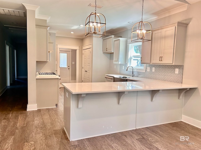 kitchen with decorative light fixtures, hardwood / wood-style floors, kitchen peninsula, and a breakfast bar