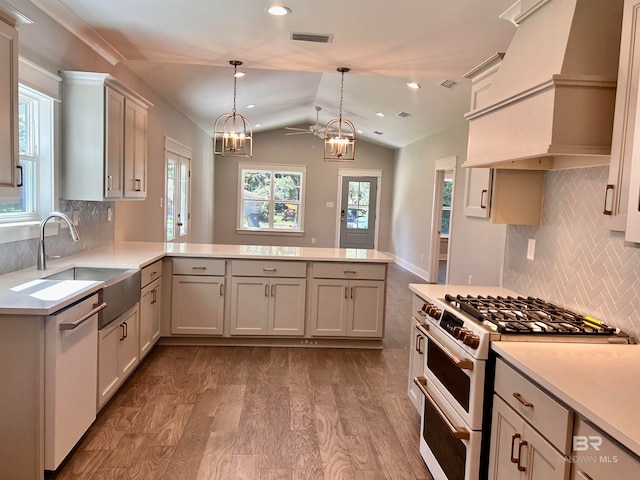 kitchen featuring pendant lighting, vaulted ceiling, kitchen peninsula, and high end stainless steel range