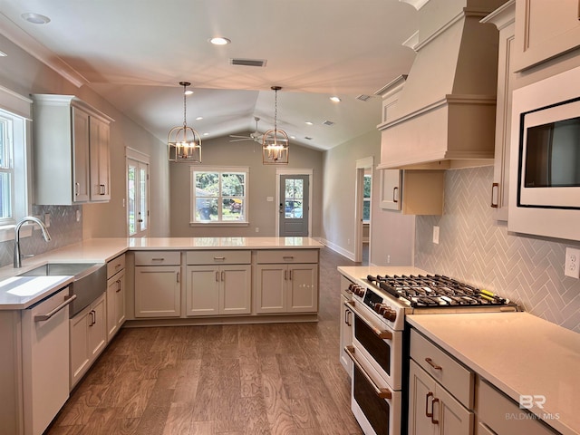 kitchen featuring kitchen peninsula, stainless steel appliances, lofted ceiling, decorative light fixtures, and a notable chandelier