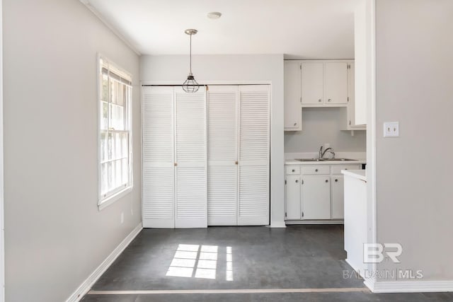 kitchen featuring pendant lighting, white cabinetry, and sink