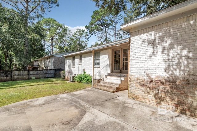 doorway to property with a lawn, a patio area, and central air condition unit