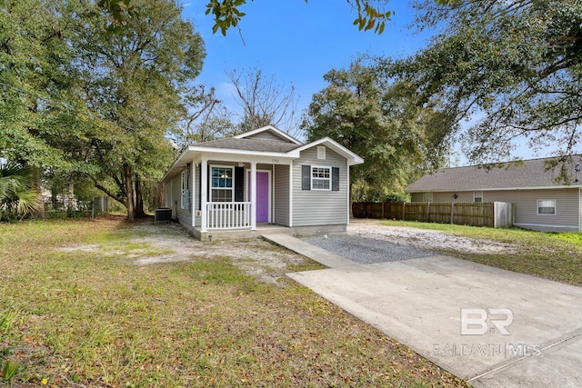 view of front of house featuring a porch, fence, cooling unit, driveway, and a front lawn