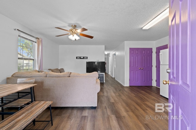 living area with a textured ceiling, a ceiling fan, and dark wood-type flooring