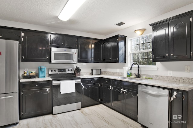 kitchen featuring appliances with stainless steel finishes, sink, and a textured ceiling