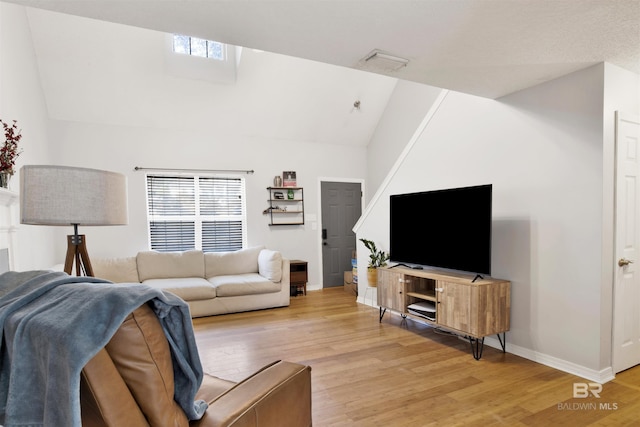 living room featuring high vaulted ceiling, light hardwood / wood-style floors, and a healthy amount of sunlight