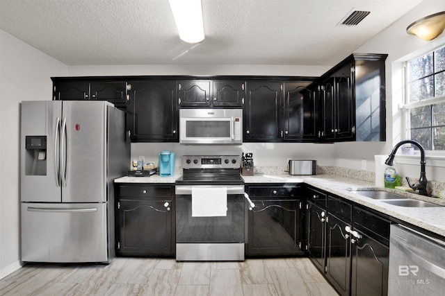 kitchen with stainless steel appliances, sink, and a textured ceiling