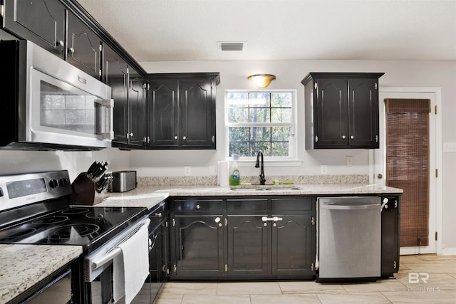 kitchen featuring stainless steel appliances, light stone countertops, and sink