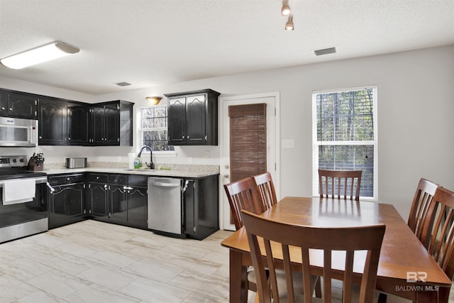 kitchen with appliances with stainless steel finishes, sink, and a textured ceiling