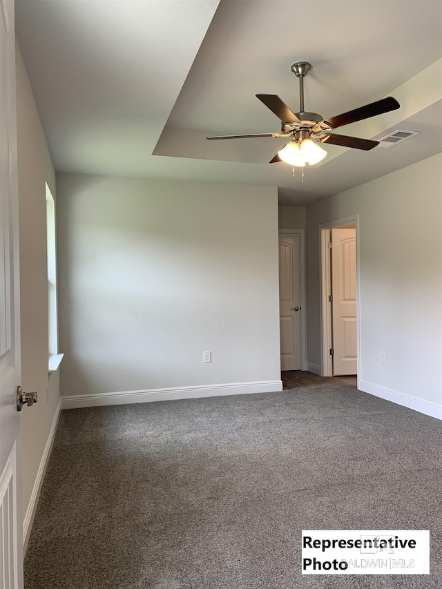 empty room with ceiling fan and dark carpet