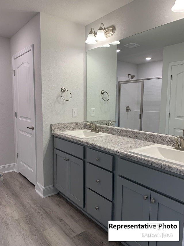 bathroom featuring hardwood / wood-style flooring, an enclosed shower, and vanity