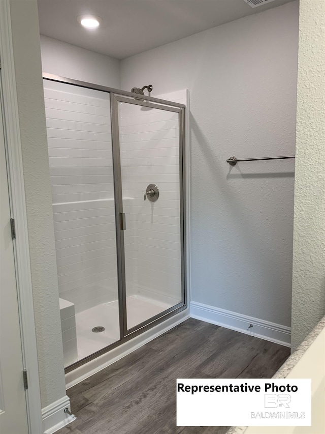 bathroom featuring a shower with shower door and hardwood / wood-style flooring