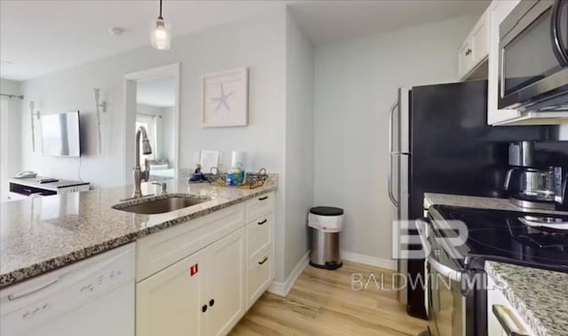 572 E Beach Blvd Unit 318, Gulf Shores, AL 36542 - kitchen with stainless steel appliances, a sink, white cabinets, and light stone counters