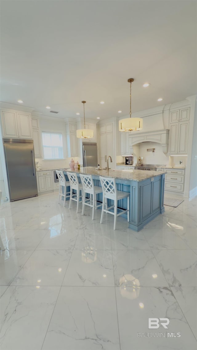 kitchen with recessed lighting, marble finish floor, a kitchen breakfast bar, and stainless steel built in fridge