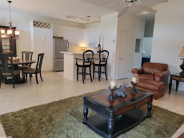 tiled living room with ceiling fan with notable chandelier