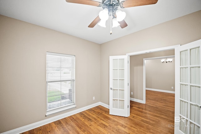 10210 Lyttleton Loop, Lillian, AL 36549 - unfurnished room featuring baseboards, french doors, ceiling fan with notable chandelier, and wood finished floors