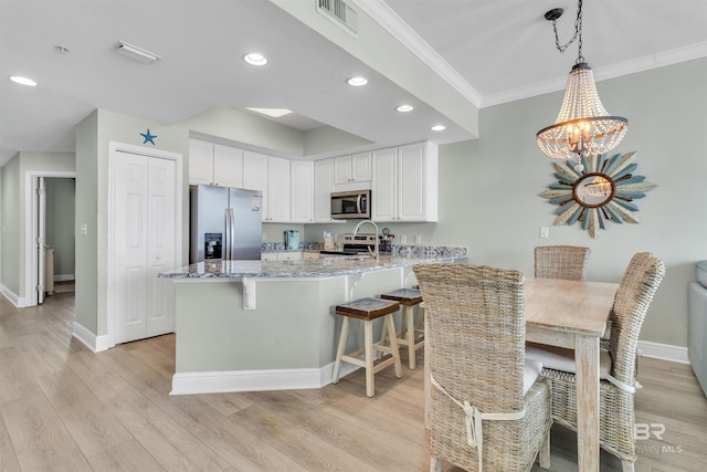 kitchen with visible vents, white cabinetry, appliances with stainless steel finishes, a peninsula, and light stone countertops