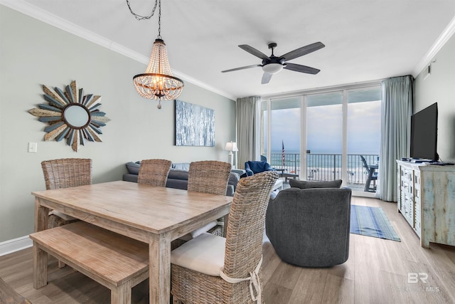 dining area featuring light wood finished floors, floor to ceiling windows, crown molding, and baseboards